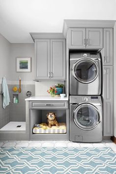 a washer and dryer in a small room with gray cabinets, rugs and blue area rug