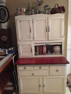 an old white cabinet with red counter top