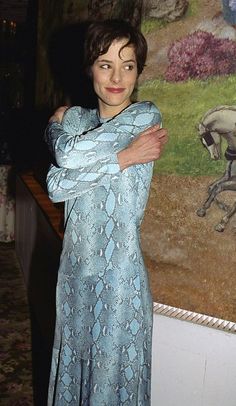 a woman standing in front of a painting with her arms crossed and looking at the camera