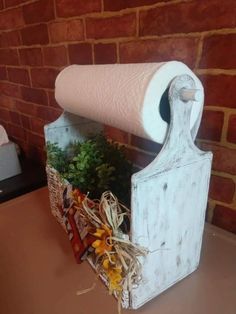 a white toilet paper holder with flowers in it on a table next to a brick wall