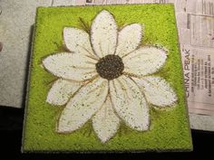 a white flower is painted on a green mat