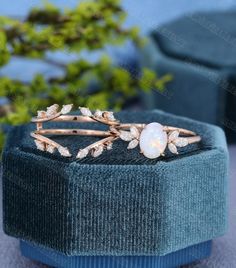 a white opal ring sitting on top of a blue velvet box next to a plant