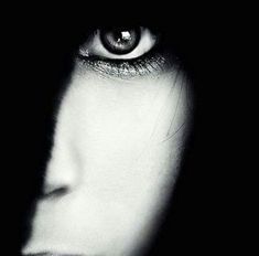 a woman's face is shown in the dark, with her eyes glowing brightly