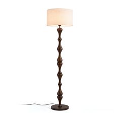 a wooden floor lamp with a white shade on the base and a cord attached to it