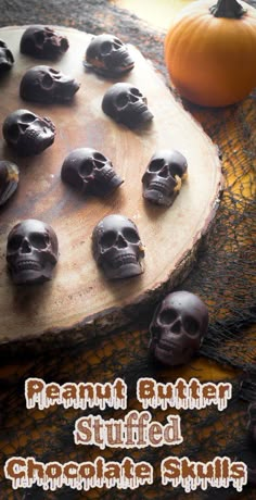 chocolate skulls are arranged on a wooden board with pumpkins in the background and text overlay that reads peanut butter stuffed chocolate skulls