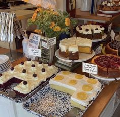 many different types of pies on display in a bakery setting with flowers and signs