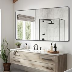 a bathroom with two sinks and a large mirror over the sink, next to a potted plant