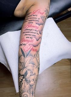 a woman's arm with flowers and words on it, sitting on a chair