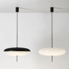 two black and white lights hanging from the ceiling in a room with no one inside