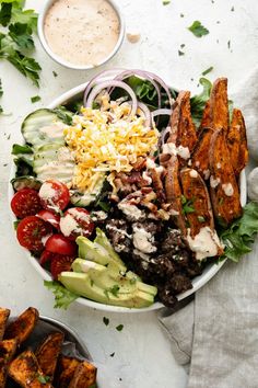 a salad with chicken, lettuce, tomatoes, cucumbers and ranch dressing