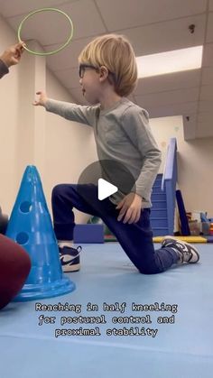 a young boy is playing with a frisbee while another child sits on the floor