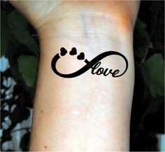 a wrist tattoo with the word love written in cursive writing and hearts on it