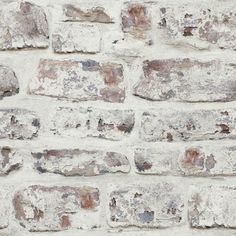 an old brick wall is shown with white paint and brown spots on the bricks,