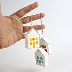 a hand holding a paper house ornament with strings attached to it's sides