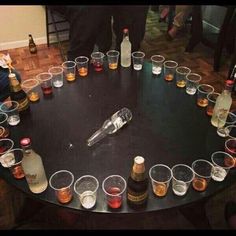 there are many glasses and bottles on the table with drinks in them, all arranged in a circle