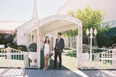 a man and woman standing in front of a white chapel