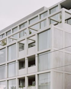 an apartment building with many windows and plants on the balconies in front of it