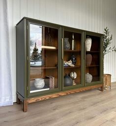 a green cabinet with glass doors on the front and bottom, sitting against a white wall