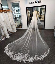 a white wedding veil with flowers on it in front of a dress shop display window