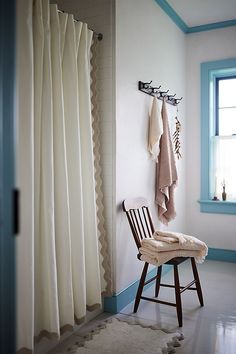 a chair sitting in front of a window next to a white shower curtain and rug