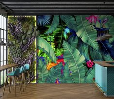 the interior of a restaurant with colorful tropical wallpaper and blue bar stools in front of it