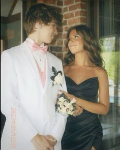 a man in a tuxedo standing next to a woman