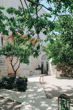 an outdoor courtyard with benches and trees in the shade on a sunny day, surrounded by greenery