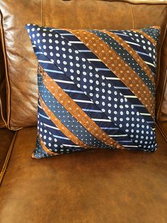 a brown leather couch with a blue and orange striped pillow on it's back