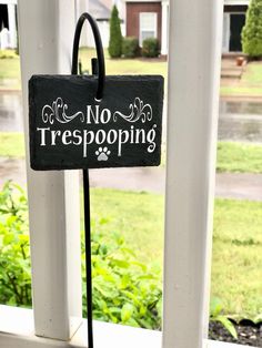 a sign that says no trespoing on it in front of a porch with flowers