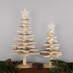 two wooden christmas trees on a table with pine cones