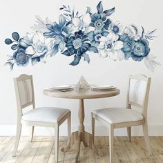 a dining room table with two chairs and a floral wall decal