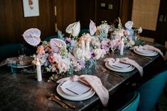 the table is set with pink flowers and place settings