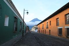 an empty street with buildings and a mountain in the backgroung, as seen from behind