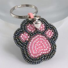 a beaded keychain with a pink and black dog's paw on it