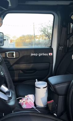 the interior of a jeep with an ice cream container and cup in it's passenger seat