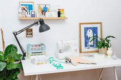 a sewing machine sitting on top of a white table next to a potted plant