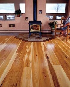 a wood burning stove in a living room with hardwood flooring and walls painted pink