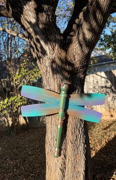 a green dragonfly sitting on the side of a tree