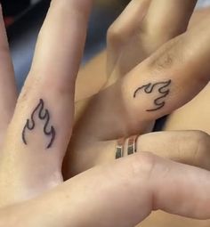 two people with tattoos on their fingers are touching each other