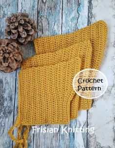 a knitted yellow mitt with two pine cones on it