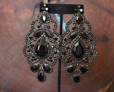 "Oversized statement earrings. These fun and stylish chandelier earrings, in black rhinestones, make a great statement piece for on stage or photos! Size of earrings: 2.25\" Wide and 4.5\" Long. Color: Black Base Metal: silver More colors available! Just message us! Style: Pierced and clip on available Looking for a matching bracelet? https://www.etsy.com/listing/556673735/crystal-wide-bracelet-royal-blue?ref=shop_home_active_9 Looking for the perfect pair of earrings for a special occasion. We Glamorous Black Crystal Earrings With Rhinestones, Glamorous Black Crystal Rhinestone Earrings, Glamorous Black Crystal Earrings, Black Rhinestone Crystal Earrings For Evening, Glamorous Black Crystal Earrings For Wedding, Black And Silver Earrings, Black Statement Earrings, Stylish Chandelier, Black Crystal Earrings