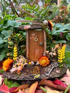 a fairy garden with an old door surrounded by flowers and plants