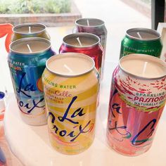 six cans of sparkling water are lined up on a table with one candle in the middle