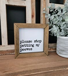 a wooden frame sitting on top of a table next to a potted plant