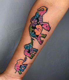 a colorful tattoo on the arm of a woman with an elephant and butterfly design in it