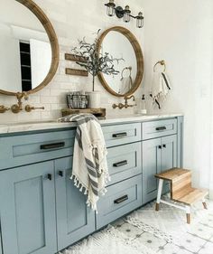 a bathroom with two round mirrors and blue cabinets