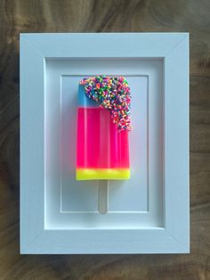 a popsicle with sprinkles in a white frame