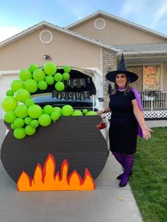 a woman in a witch costume standing next to a sign with tennis balls on it