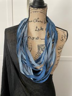 a mannequin wearing a blue scarf on top of a black dress shirt with words written on it