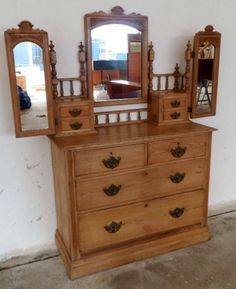 an antique dresser with mirror and two mirrors on it's sides, in front of a white wall